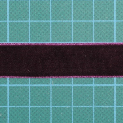 Fita de veludo castanha escura com bordas cor-de-rosa sobre superfície verde quadriculada