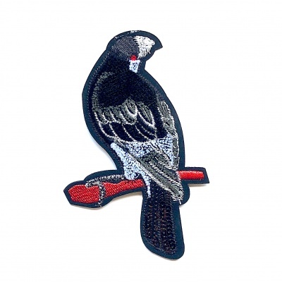 Aplicação bordada de pássaro preto, cinza e branco sobre galho vermelho