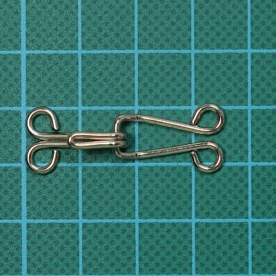 Fecho metálico prateado sobre base verde com grade azul.