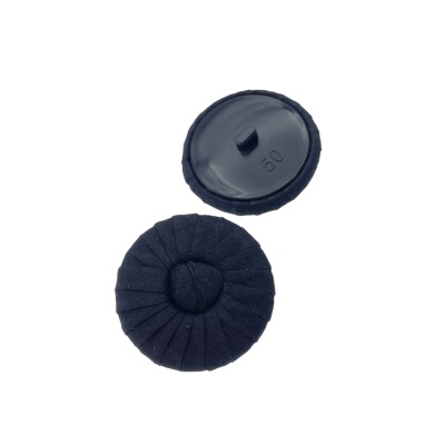 Dois botões redondos pretos, um com tecido franzido e outro com parte de trás em plástico e número '50' gravado