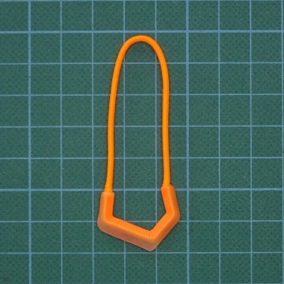 Cabo de silicone laranja com formato angular sobre superfície verde quadriculada