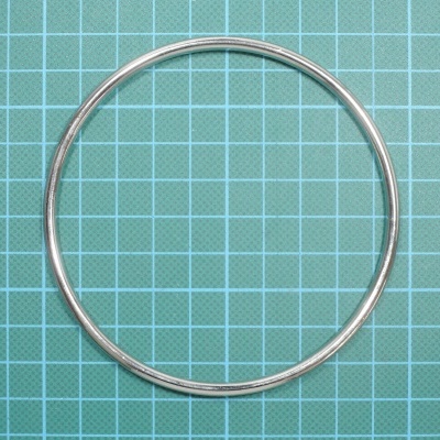 Anel metálico prateado sobre superfície azul quadriculada