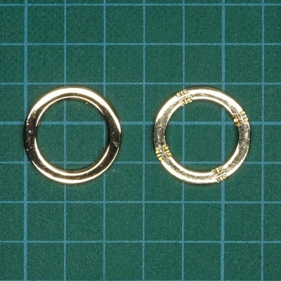 Duas argolas douradas circulares sobre superfície verde quadriculada