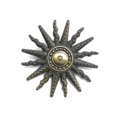 Broche metálico em forma de sol com raios alternados em cinza e dourado