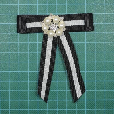 Laço de fita preta e branca com adorno de pérolas