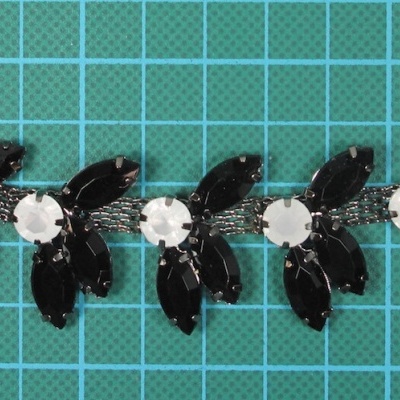 Colar decorativo preto e branco com pedras acrílicas sobre base verde quadriculada