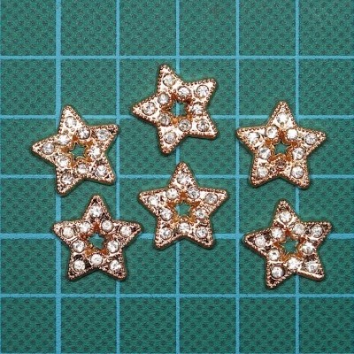 Cinco acessórios em forma de estrela dourada com pedras brancas sobre fundo de grade azul