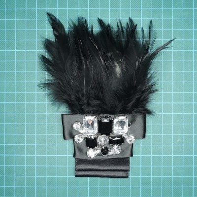 Acessório com penas pretas, fita preta e pedras decorativas