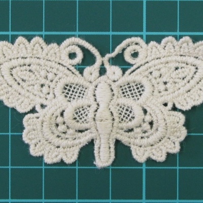 Aplicação branca em renda em forma de borboleta sobre fundo verde com grelha branca