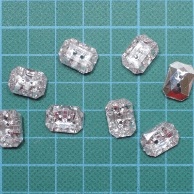 Botões pequenos transparentes faceteados sobre base verde quadriculada