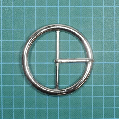 Fivela circular metálica prateada em tapete verde quadriculado