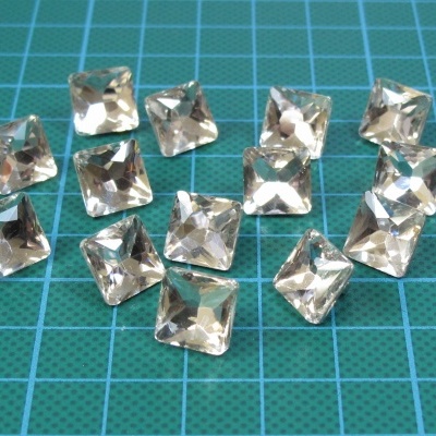 Pedras quadradas transparentes facetadas sobre superfície de corte azul com grelha branca