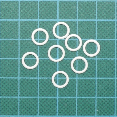 Dez anéis brancos pequenos sobre base verde quadriculada