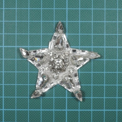 Estrela decorativa transparente com contas sobre superfície verde quadriculada