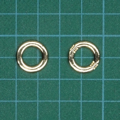 Duas argolas metálicas douradas sobre fundo verde com grade azul