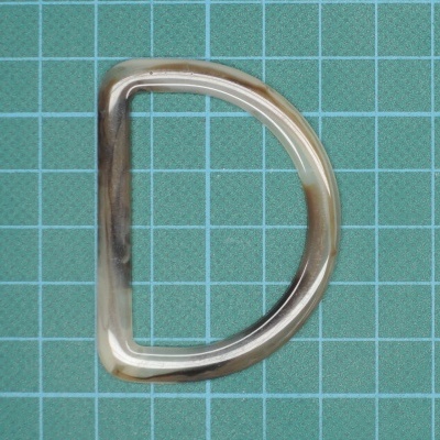 Anel D metálico prateado sobre grade verde