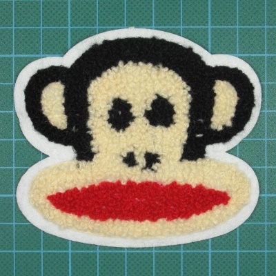 Patch tecido com cabeça de macaco felpuda em preto, bege e vermelho