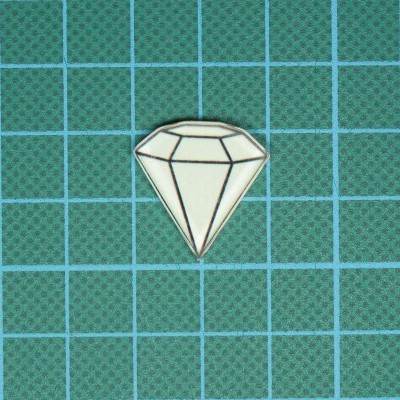 Pin esmaltado em forma de diamante branco sobre superfície verde quadriculada