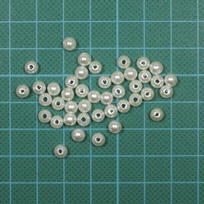 Contas redondas pérola pequenas sobre superfície verde quadriculada