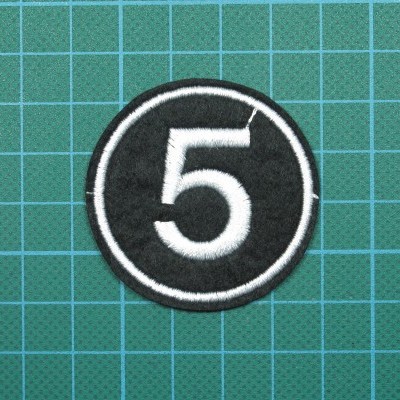 Emblema bordado preto com número 5 branco sobre fundo quadriculado azul e cinza