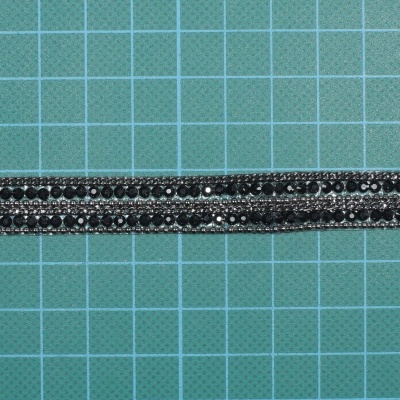 Fita decorativa preta com pedras brilhantes sobre fundo quadriculado verde
