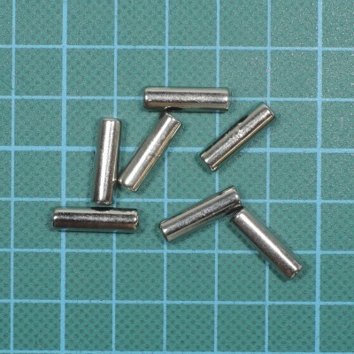 Pequenos cilindros metálicos prateados sobre fundo quadriculado azul e verde