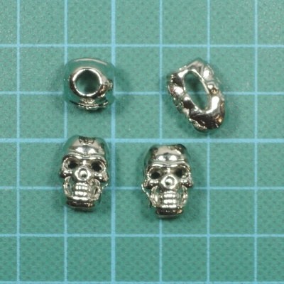 Contas metálicas prateadas em forma de caveira sobre fundo quadriculado azul