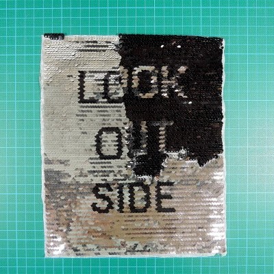 Capa quadrada com lantejoulas preta e prateada com texto 'LOOK OUT SIDE'