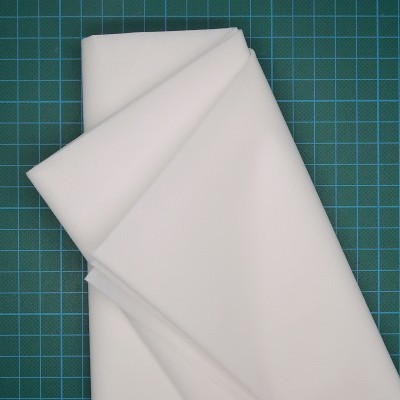 Tecidos brancos dobrados sobre superfície verde com padrão de grelha em quadrados