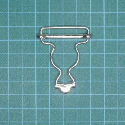 Clipe metálico prateado sobre superfície quadrada azul