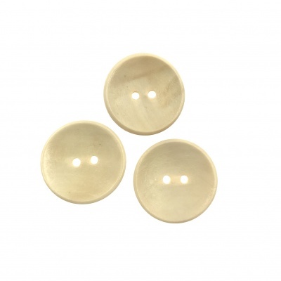 Três botões bege claros redondos com dois orifícios em fundo branco