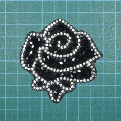 Aplicação em forma de flor com lantejoulas pretas e brilhantes prateados