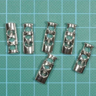 Sete conectores metálicos prateados sobre superfície quadriculada verde