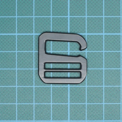 Objeto metálico prateado retangular com três barras horizontais sobre fundo quadriculado azul