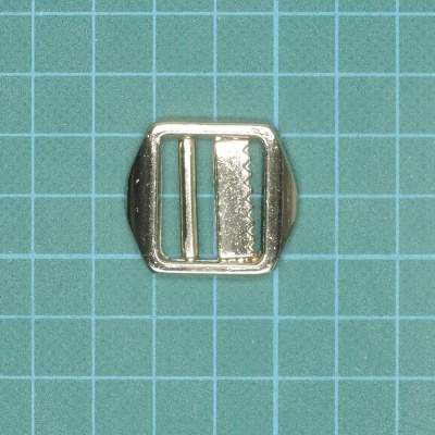 Fivela de metal prateado sobre superfície com grelha azul