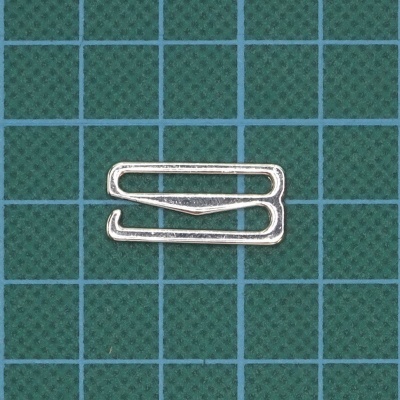 Clipe metálico prateado em fundo verde com padrão de grelha azul