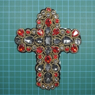 Broche ou pendente cruz com pedras coloridas sobre fundo verde com grade