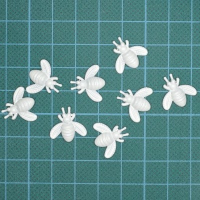 Pequenas figuras de abelhas brancas sobre base quadriculada