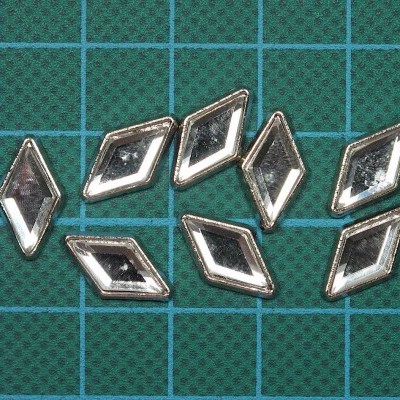 Pequenos losangos metálicos espelhados sobre superfície quadriculada verde