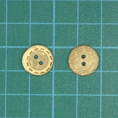 Dois botões pequenos bege sobre fundo verde quadriculado