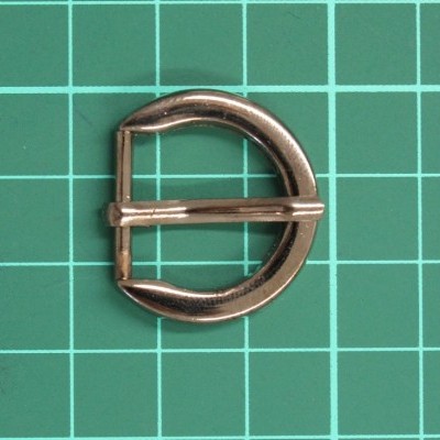 Fivela metálica dourada em forma de D sobre superfície verde com grelha branca