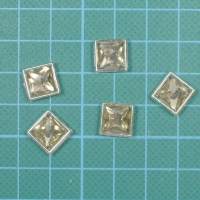 Cinco botões quadrados transparentes com rebordo dourado sobre fundo azul quadriculado