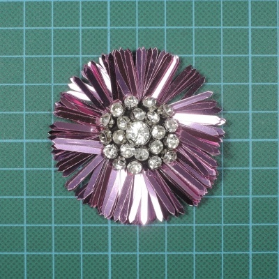 Flor metálica rosa decorativa com pedras brilhantes no centro