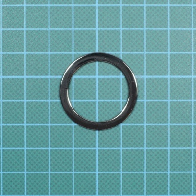 Anel metálico preto sobre superfície quadriculada verde