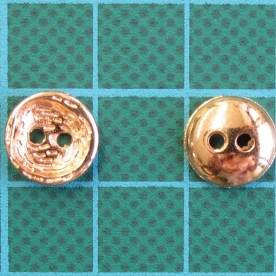 Dois botões dourados redondos sobre fundo verde com padrão quadriculado.