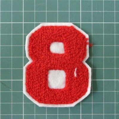 Patch número 8 vermelho com bordas brancas sobre fundo quadriculado verde