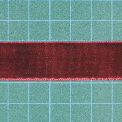 Fita de cetim vermelha com bordas douradas sobre superfície verde quadriculada