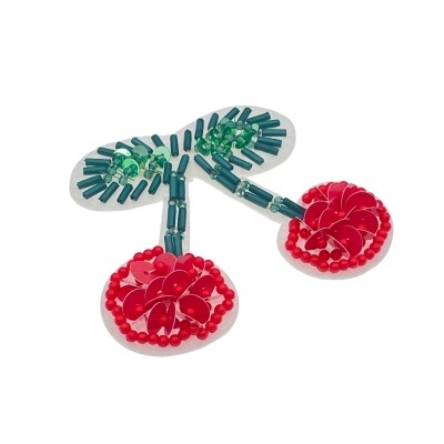 Broche em forma de cereja com contas verdes e vermelhas em fundo branco