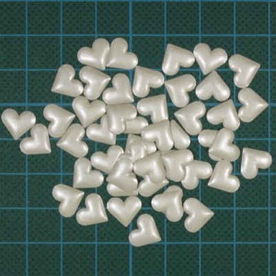 Pequenos corações brancos sobre superfície verde com grelha