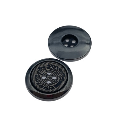 Dois botões pretos brilhantes, um com padrão texturizado e símbolo ornamental